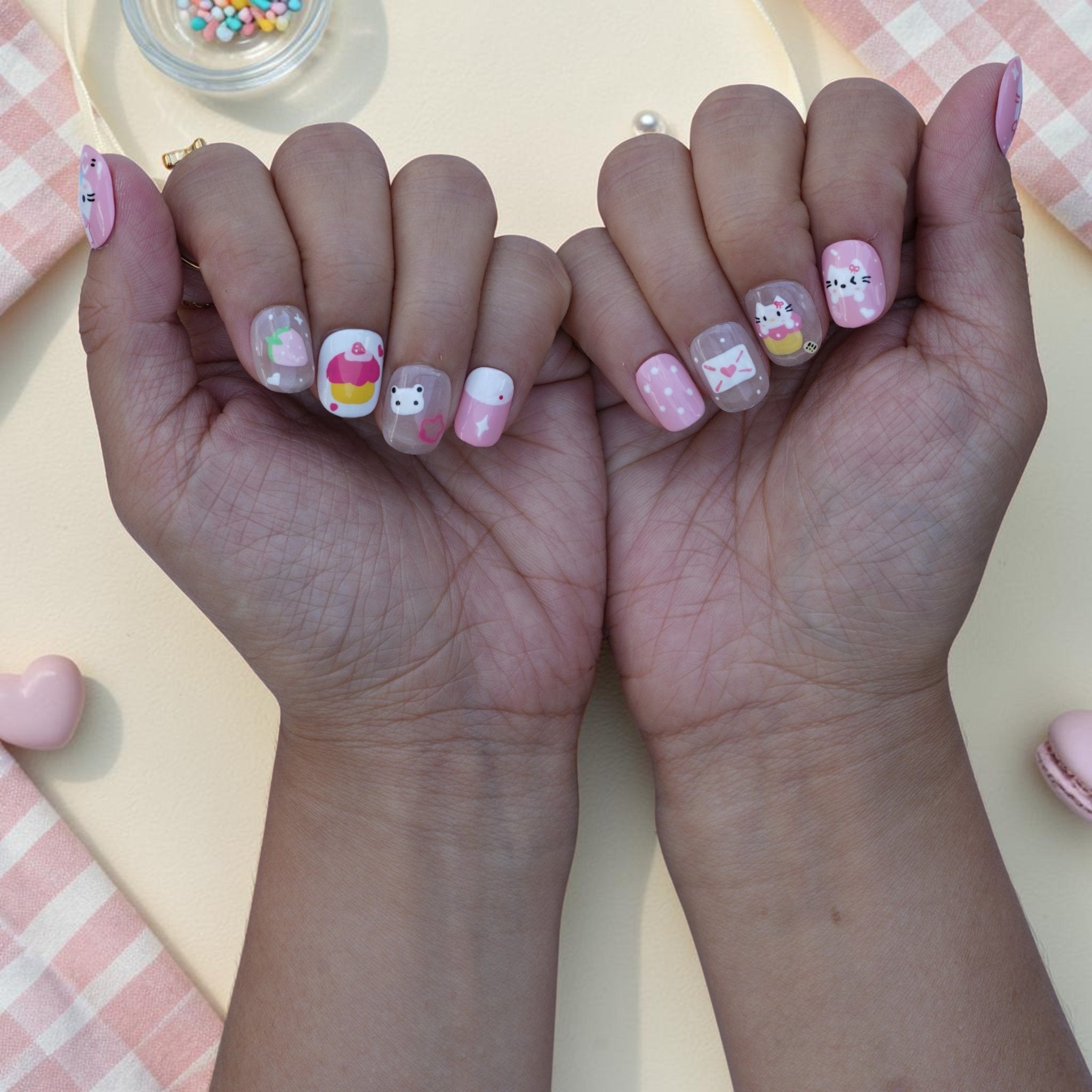 Cute cat press on nails shown on both hands with kittens, cupcakes and hearts