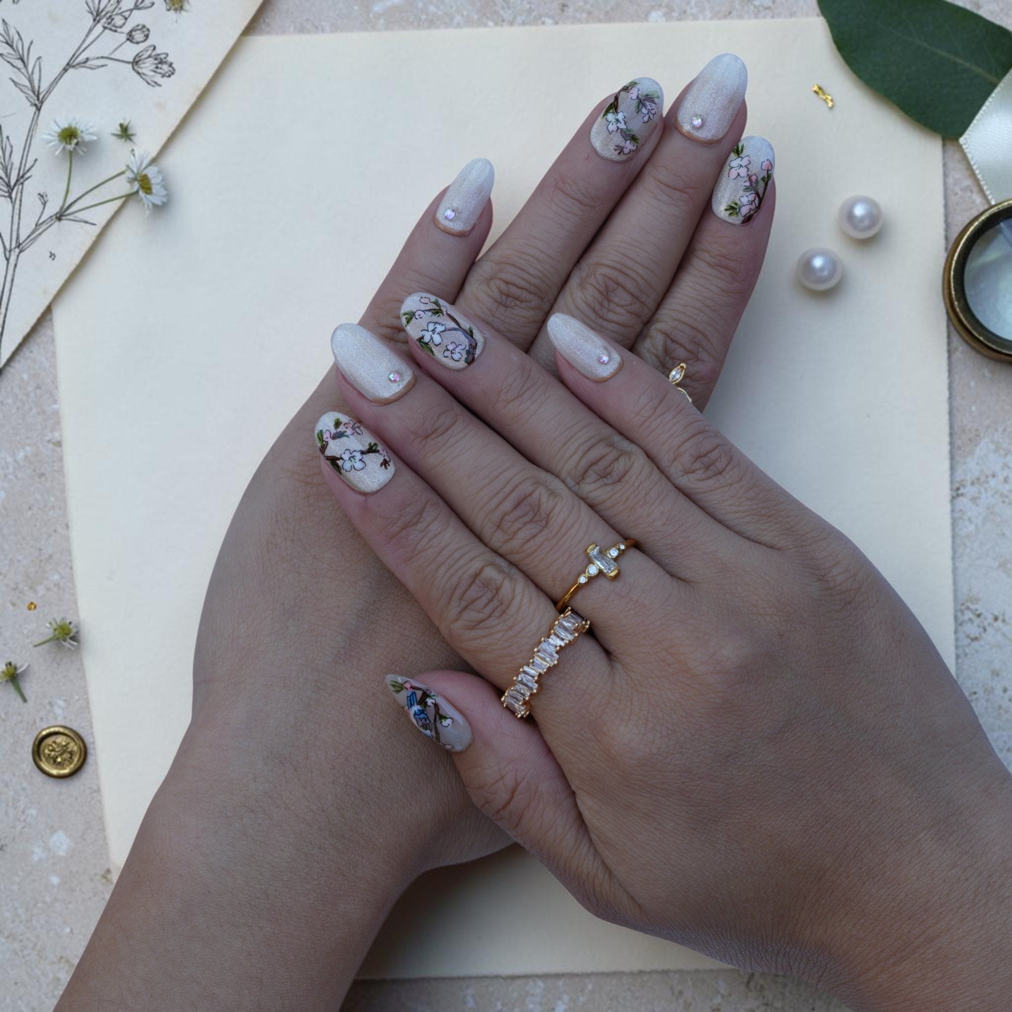 Vintage bird press on nails worn on hand with painted songbirds, blossoms and gold rings