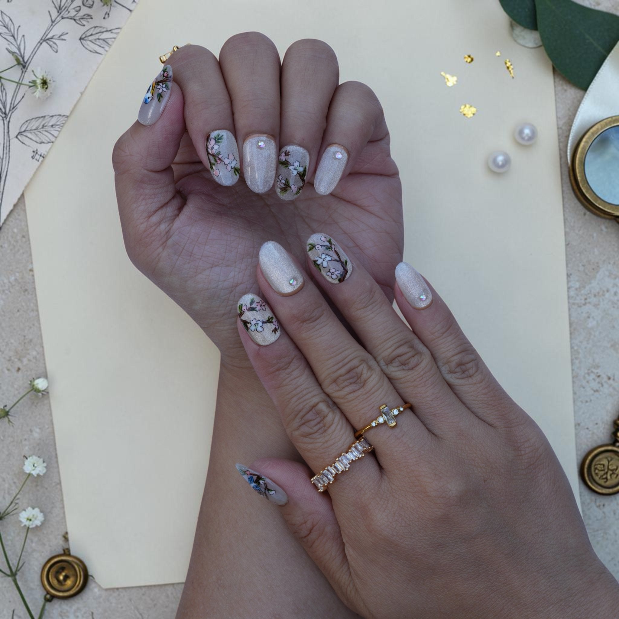Oval bird press on nails close up with songbirds, pink blossoms and a crystal accent