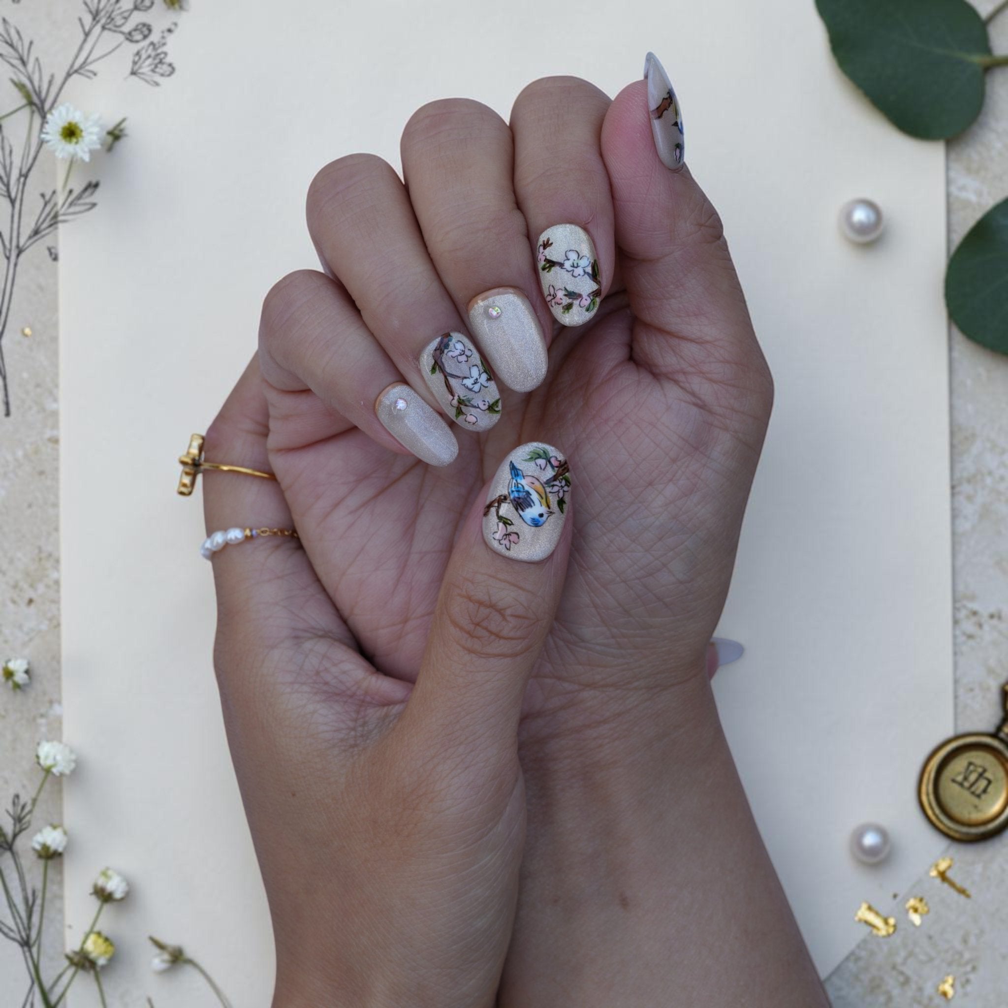 Vintage botanical press on nails with painted birds and blossom on a shimmer base