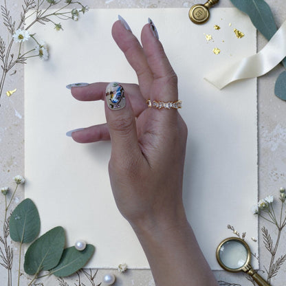 Nightingale press on nails styled on hand with songbirds, blossoms and pearls