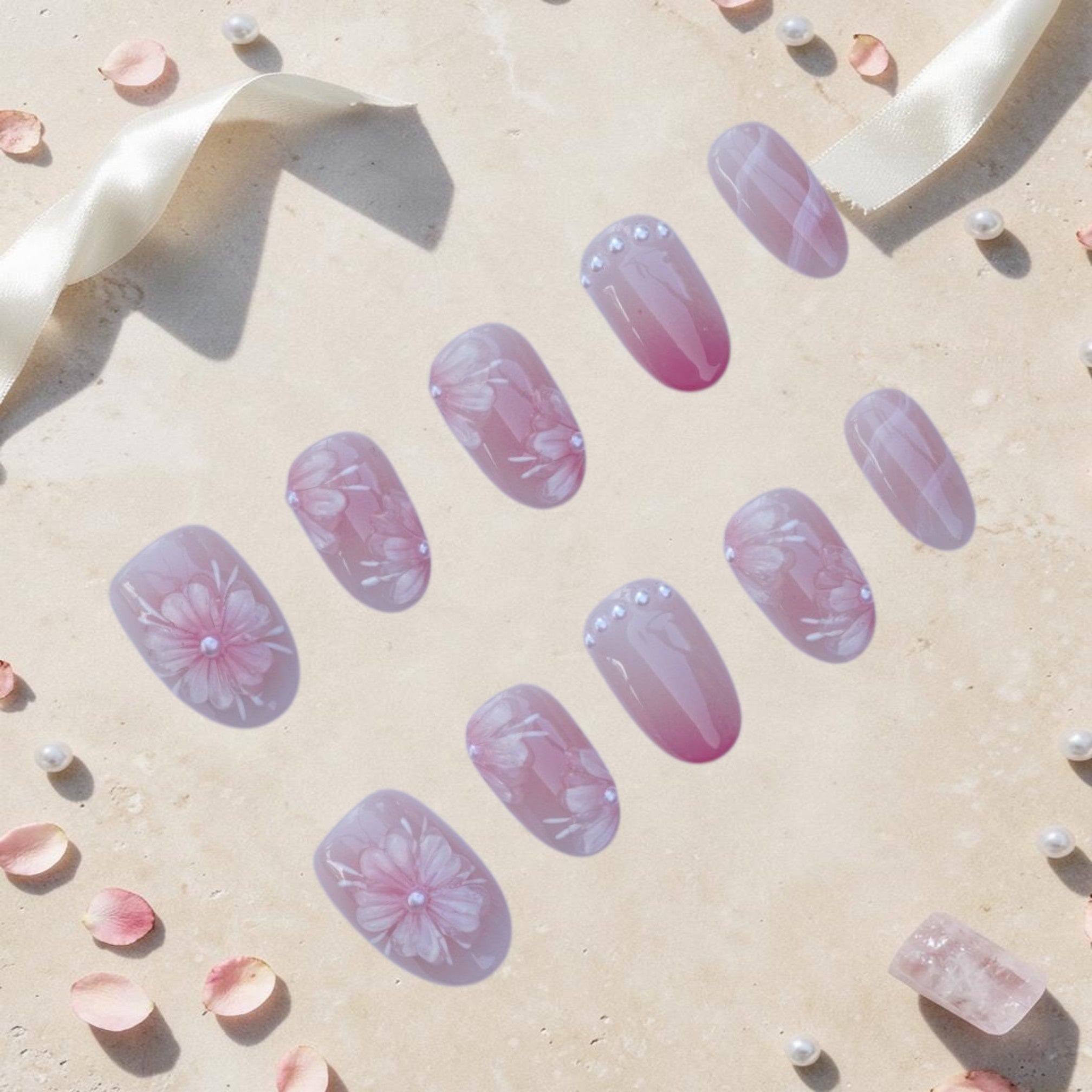 Handmade cherry blossom press on nails flat lay in soft pink with hand painted blossoms, pearl centres and rosy ombre