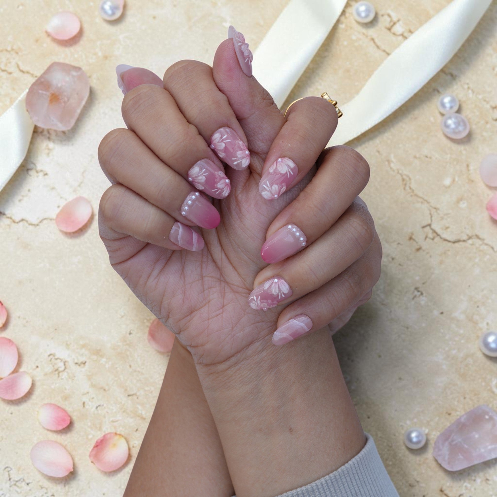 Romantic pink blossom press on nails with pearl centres shown on both hands