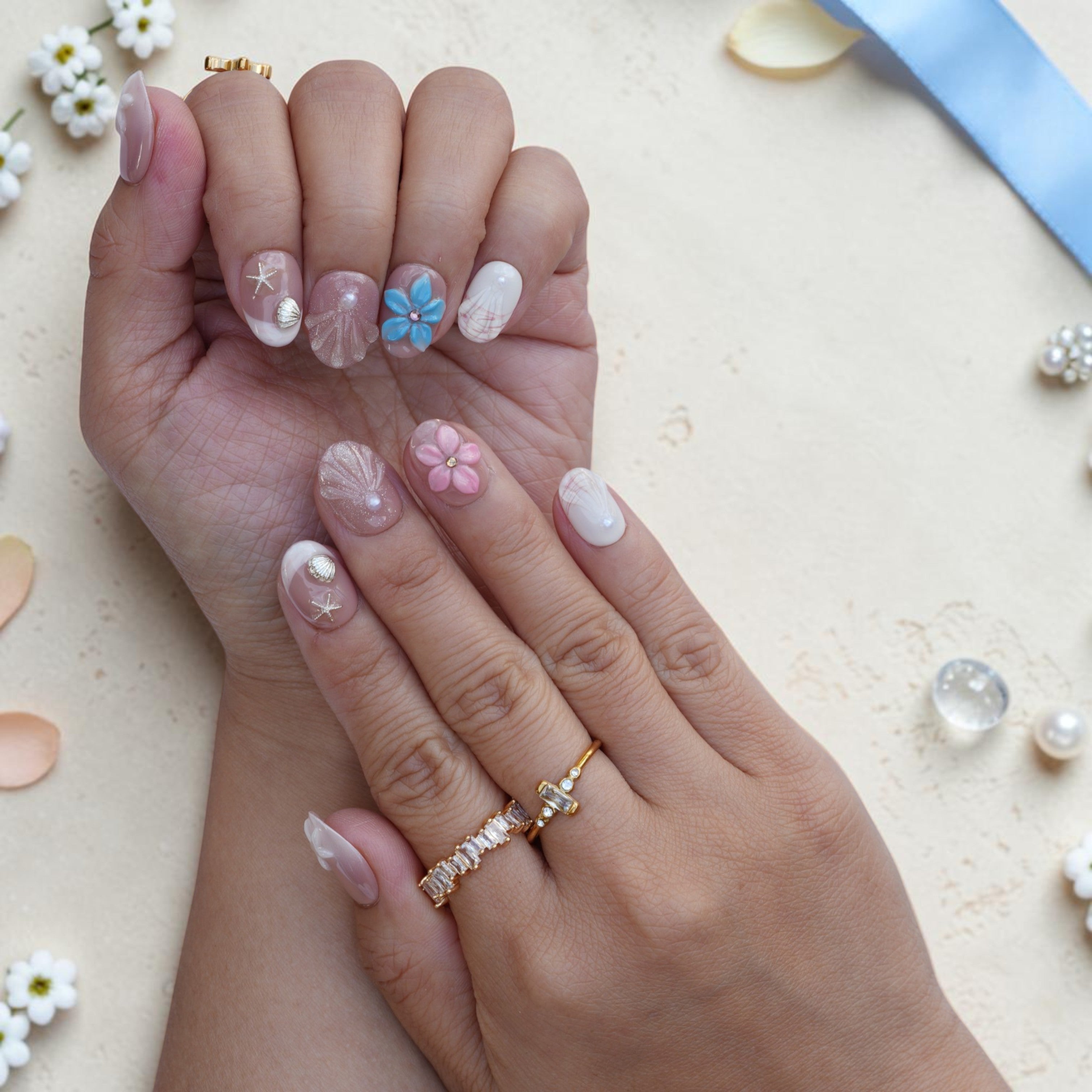 Mermaid press on nails close up with sculpted seashells, starfish charms and pink flowers