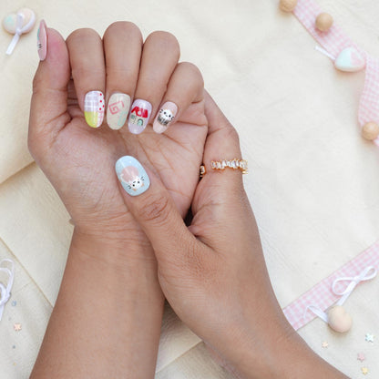Hand wearing cat press on nails with a coffee cup kitten