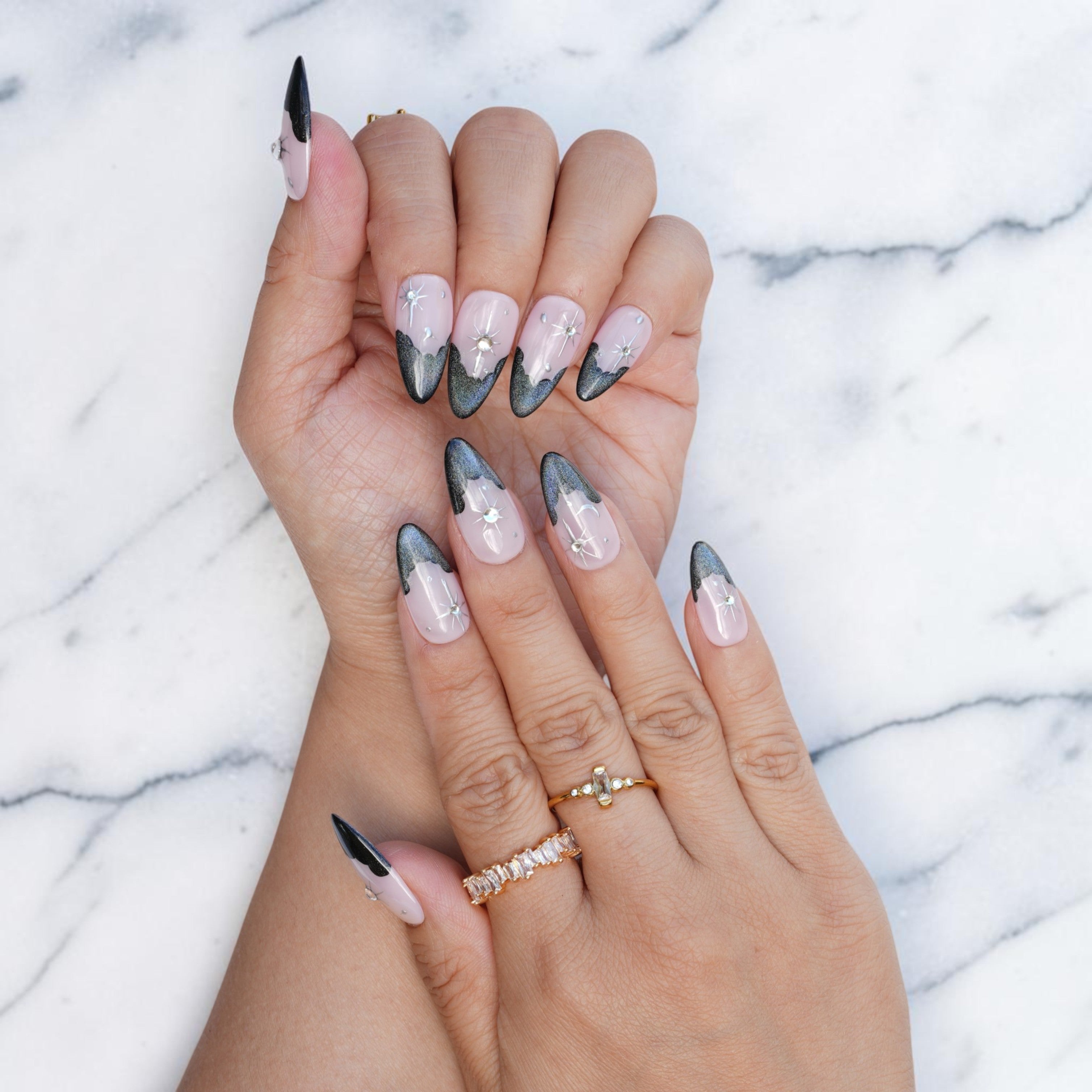 Hand wearing black French tip nails with a celestial star and rhinestone