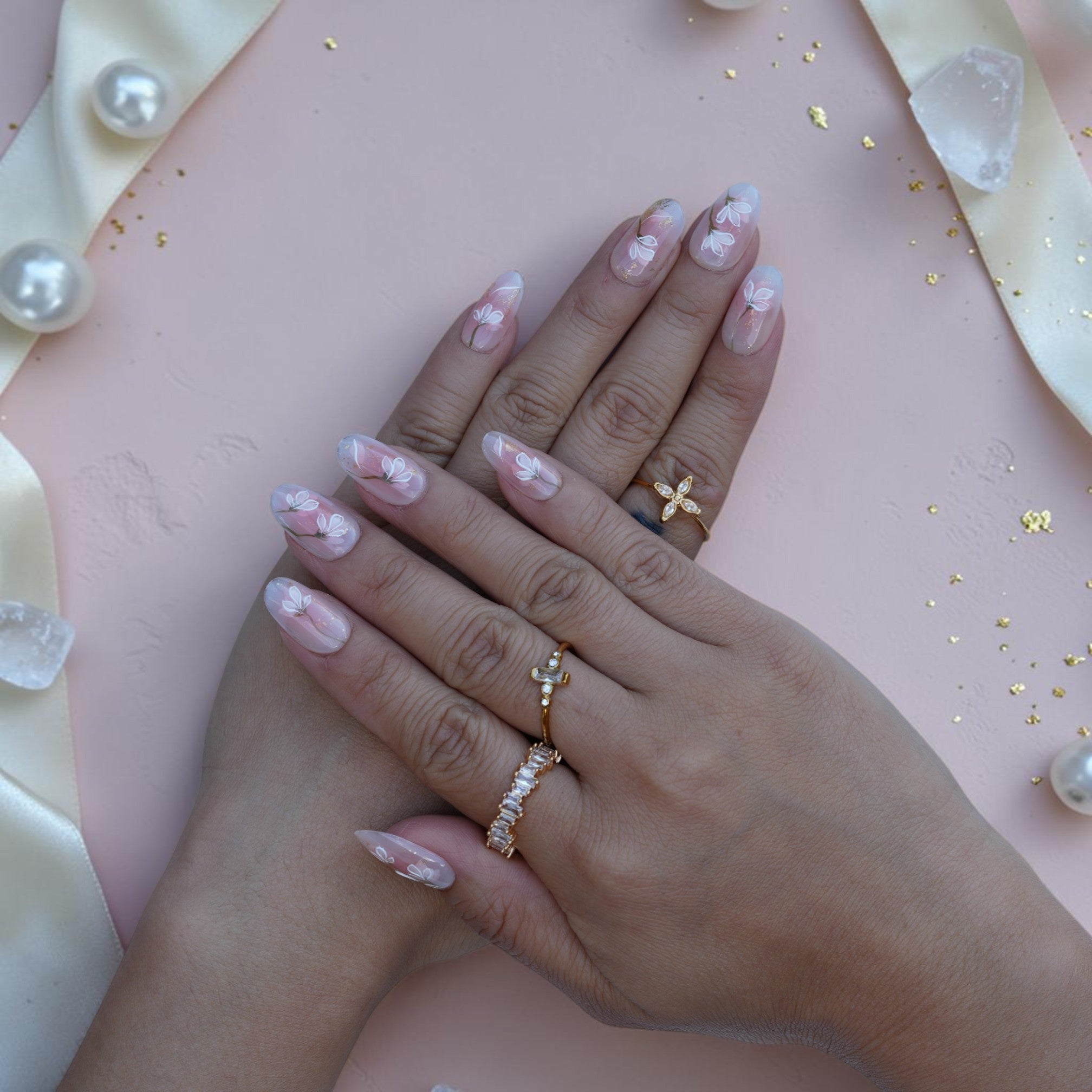 Hand wearing sheer nude press on nails with hand painted white magnolia flowers