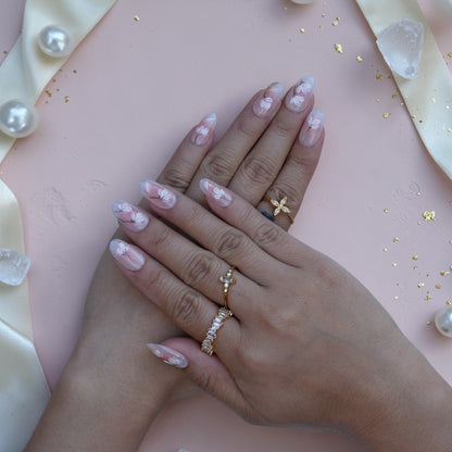 Hand wearing sheer nude press on nails with hand painted white magnolia flowers