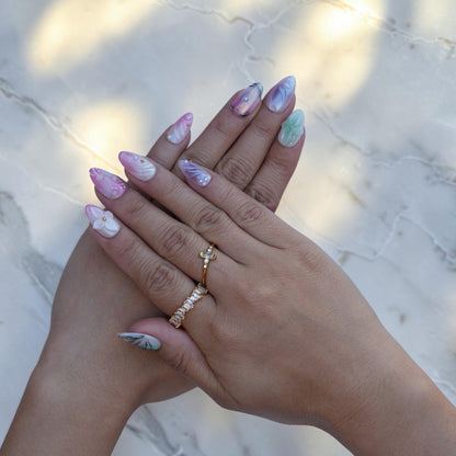 Hand wearing pastel press on nails with a mint 3D flower and pink shimmer