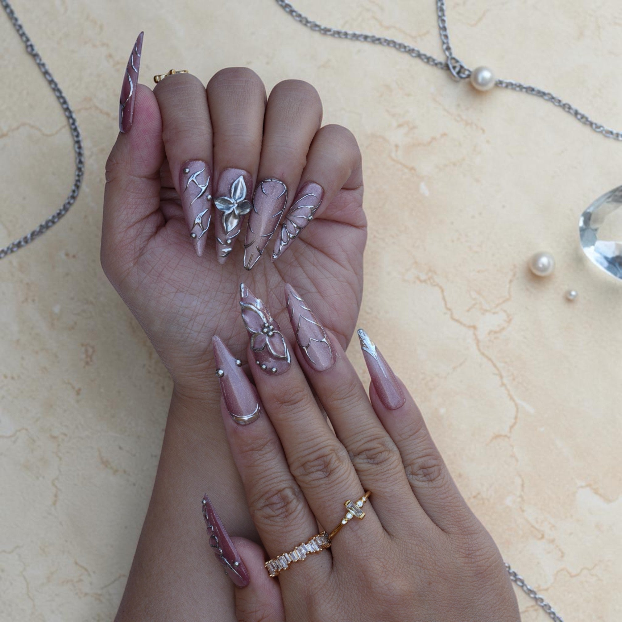 Close up of a silver wire butterfly wing on a mauve velvet press on nail