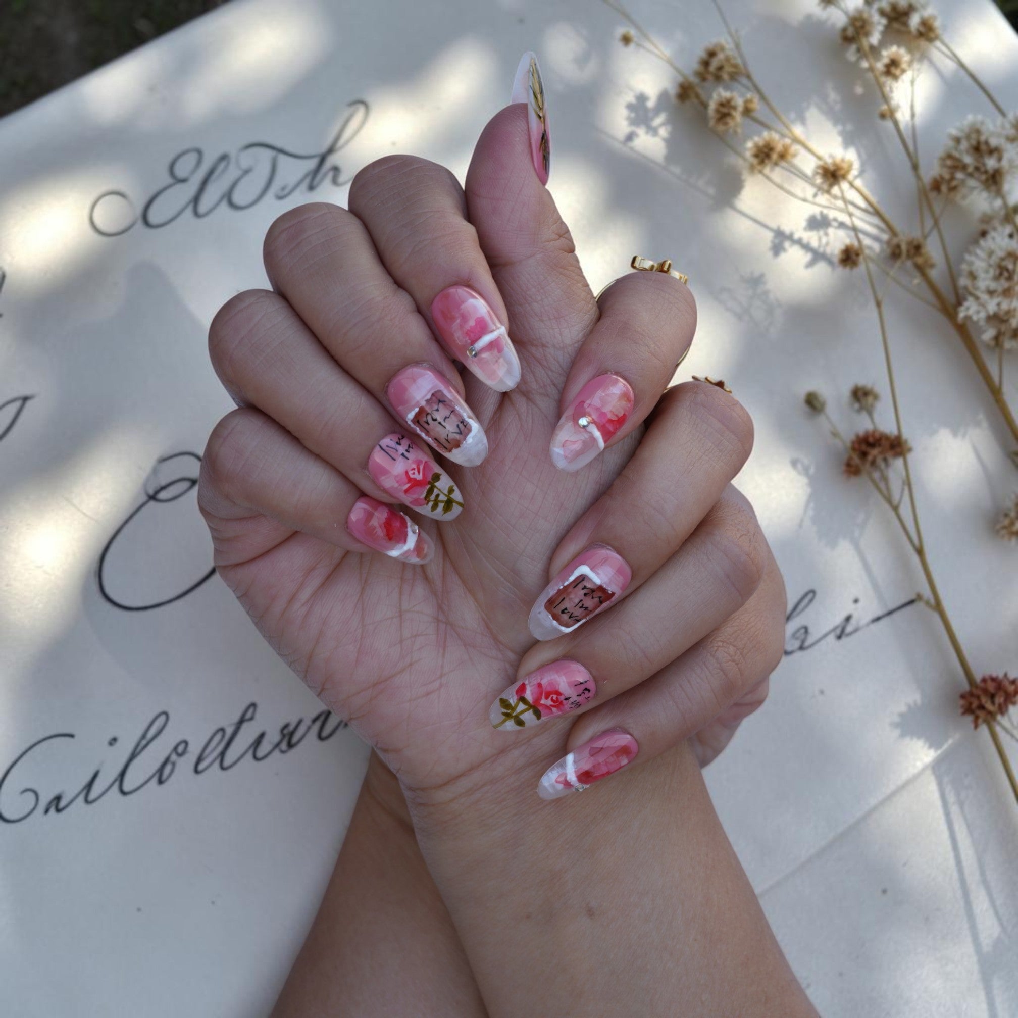 Close up of watercolour roses and love letter script on a blush nail