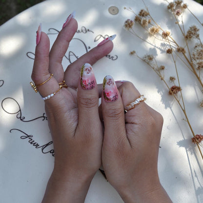 Soft pink almond nails with rose art and a small gemstone