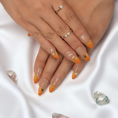Full view of both hands wearing Sunset Nova press on nails, decorated with celestial gold moons and pearls