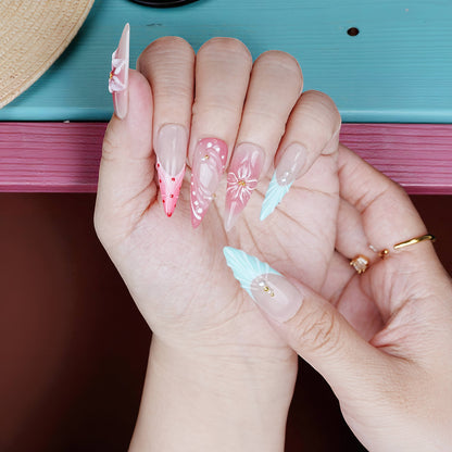 Close-up of pink ombre press on nails with 3D floral designs and glitter tips, summer beach vibe