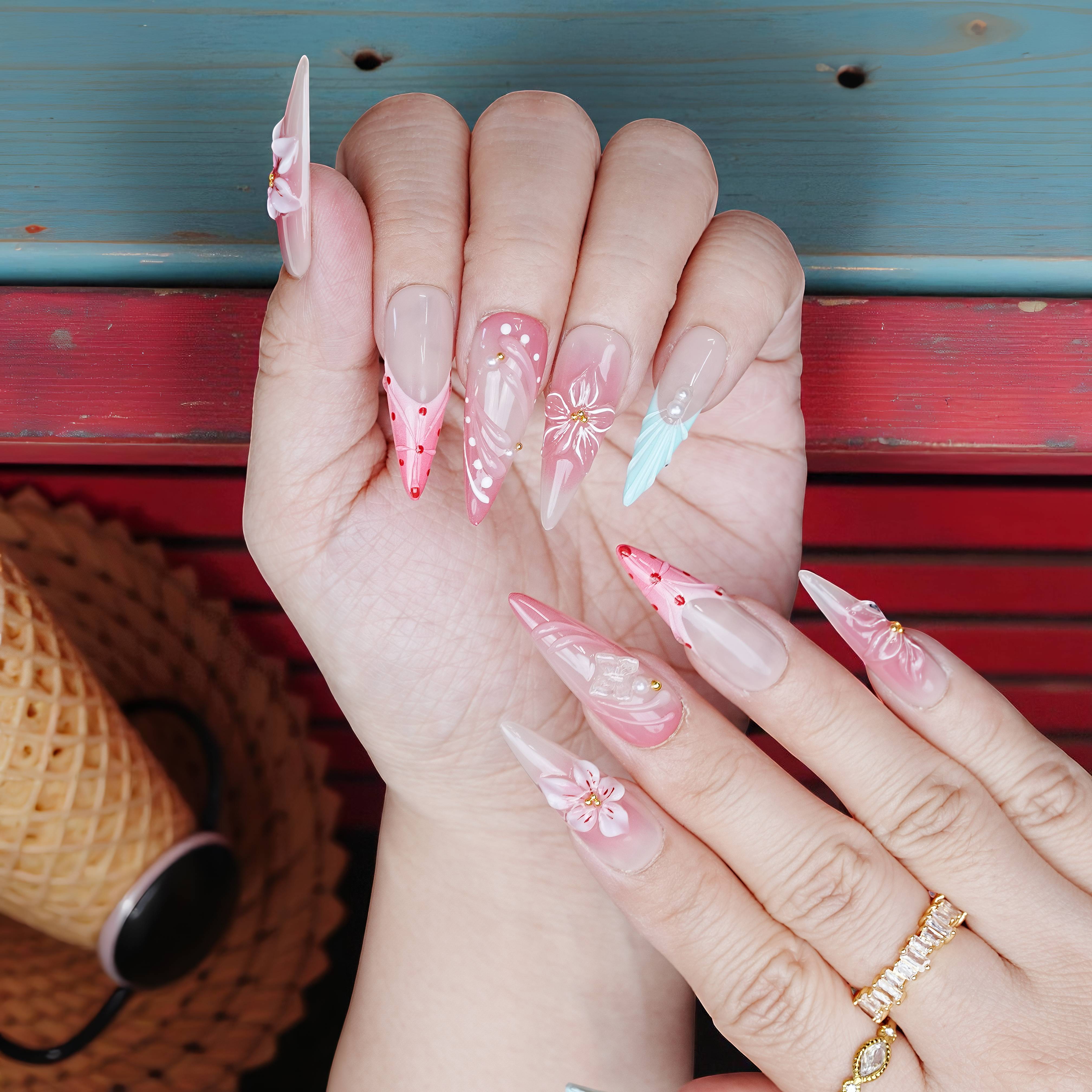 Dual-hand view of long almond-shaped press on nails in coral pink and aqua blue with tropical designs