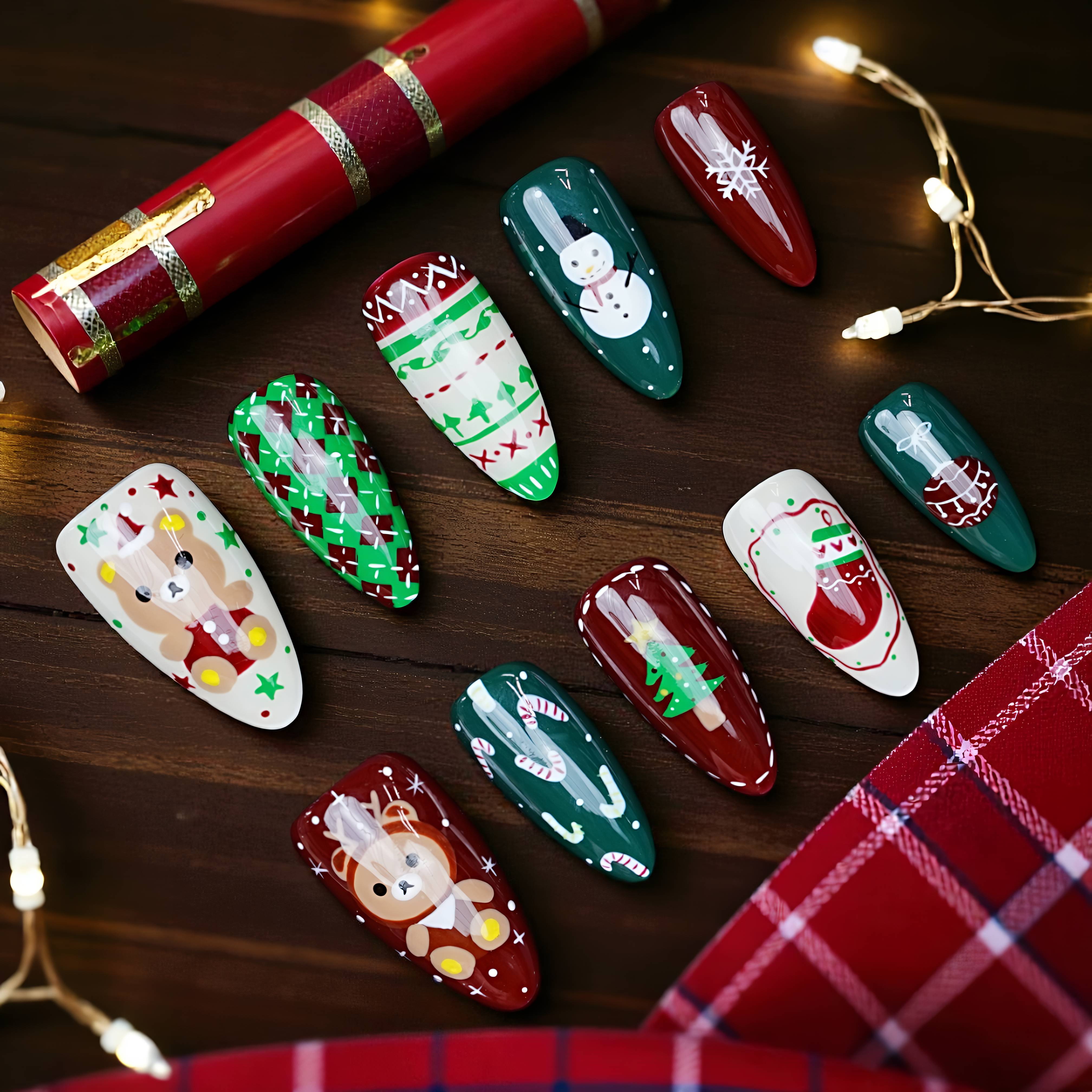 Flat lay of Christmas press on nails featuring Santa, snowflakes, candy canes, green knit patterns, and gingerbread men on dark wood background