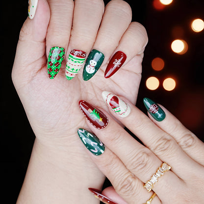 Hands wearing festive press on nails with red, green, and white patterns including holiday characters and sweater art.