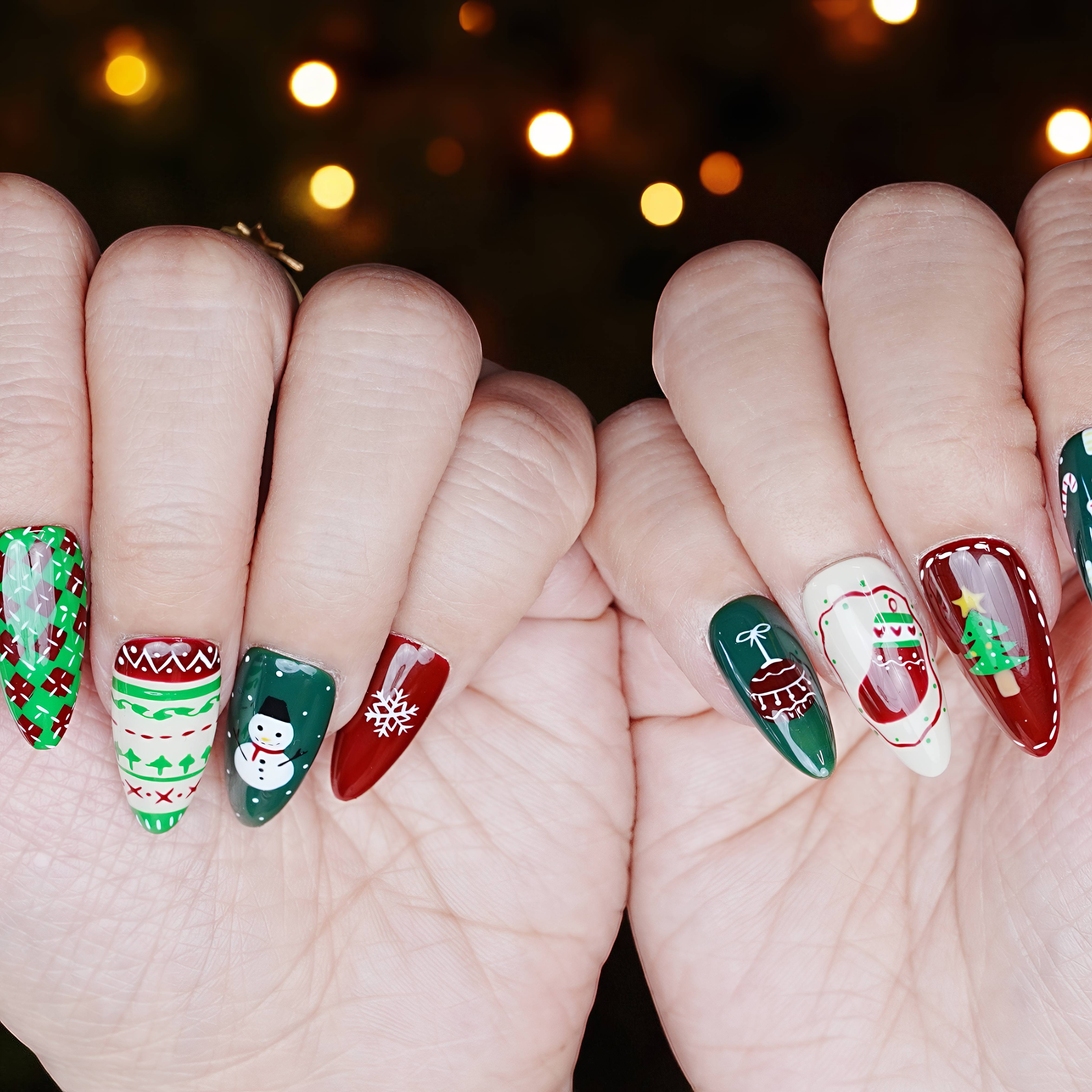 Close-up of Santa-themed nails with red shimmer and hand-painted winter art on long almond shapes.