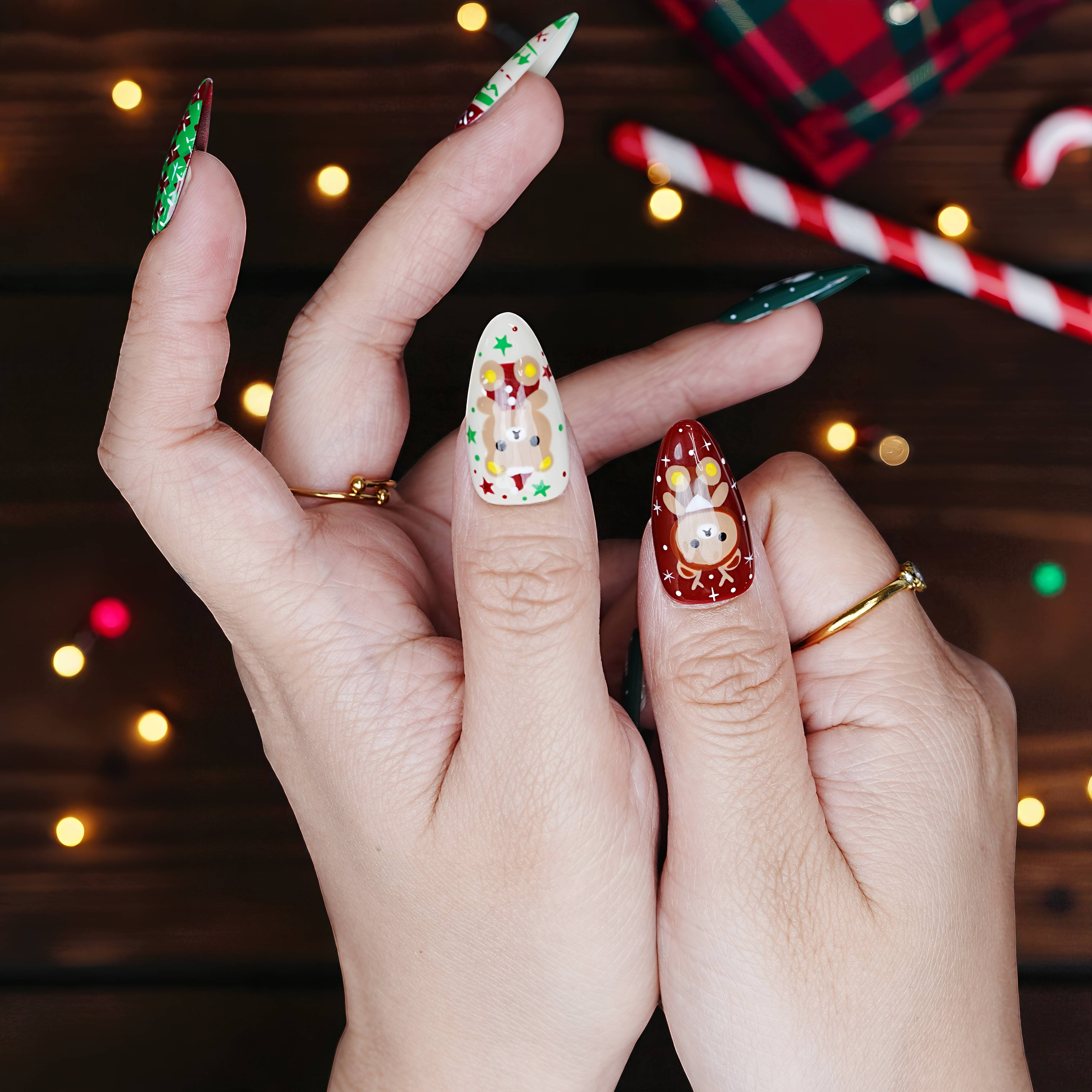 Candy cane holding shot showcasing Christmas press on nails with snowflake, present, and sprinkle cookie details.