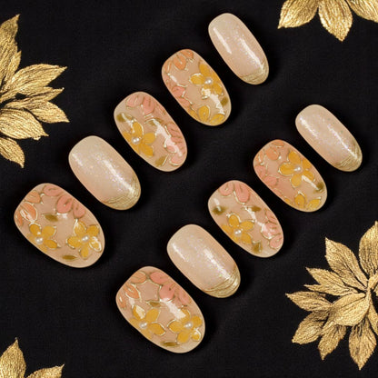 Handcrafted press on nail set featuring peach and yellow floral patterns with gold details and glossy finish. Glue on nails Australia