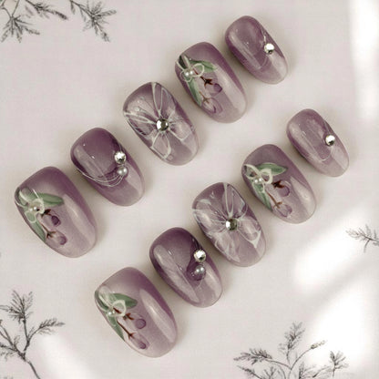 Purple flower press on nails set displayed with hand-painted blossoms, crystals, and a lavender ombré base. Reusable stick on nails Australia