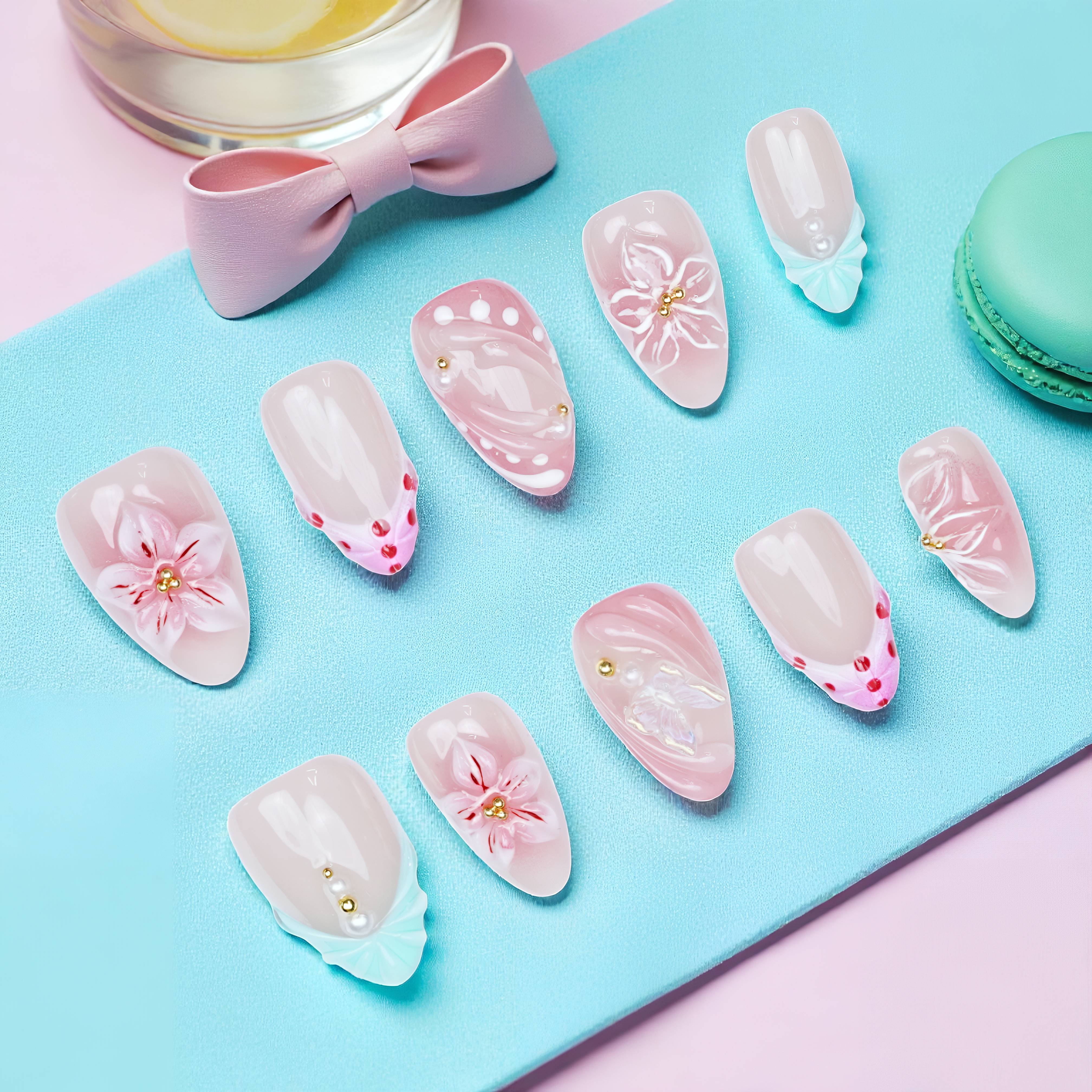Top-view layout of press on nails featuring soft pink polish, white 3D flowers, and heart dot accents on a pastel background
