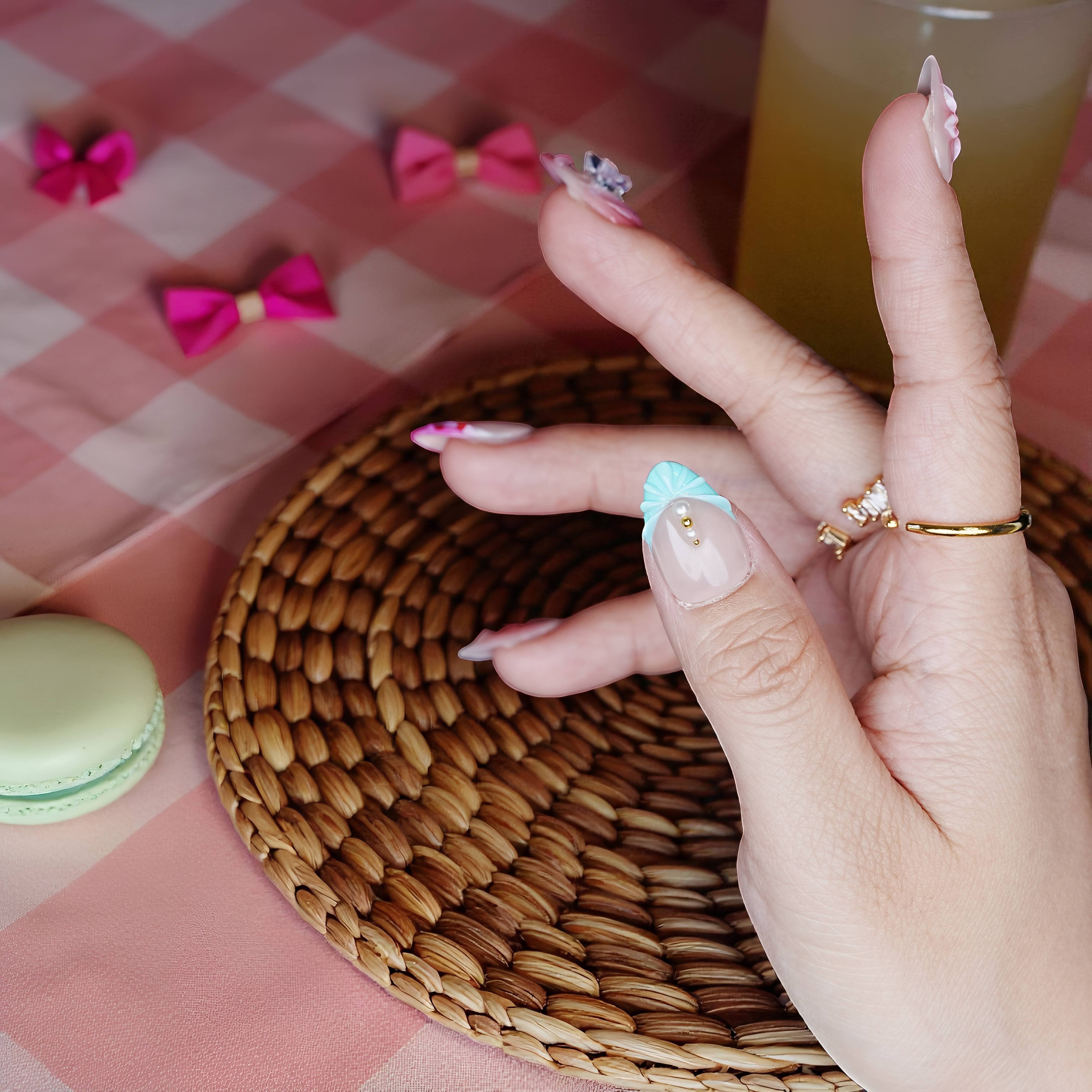 Side angle showing sculpted nails with heart dot design and pearlescent pastel finish.