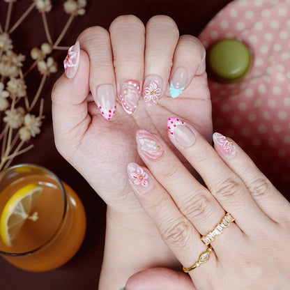 Both hands with full Peachy Petal nail set under warm light, highlighting heart details and shimmer.
