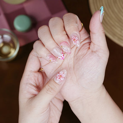 Palms up showing pink floral press on nails with dot and swirl detailing and a glossy topcoat.