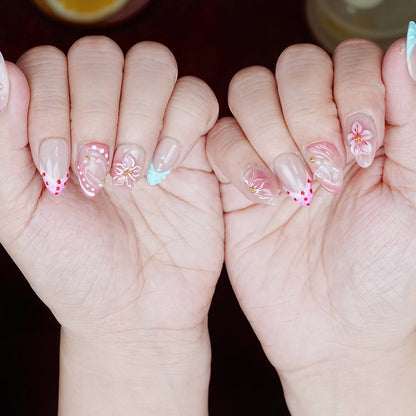 Even lighting showing soft pastel pink nails with 3D flowers, mint leaf accent, and dotted hearts.