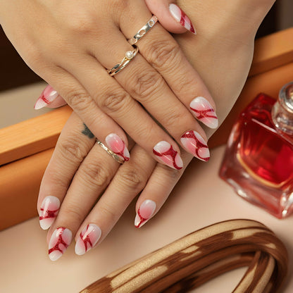 Reusable glue on nails with bold red glitter curves, applied to natural hands with perfume bottle backdrop, perfect for gifting.