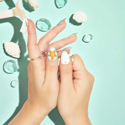 Seahorse and starfish adorned beach press on nails with soft shimmer and translucent overlays.