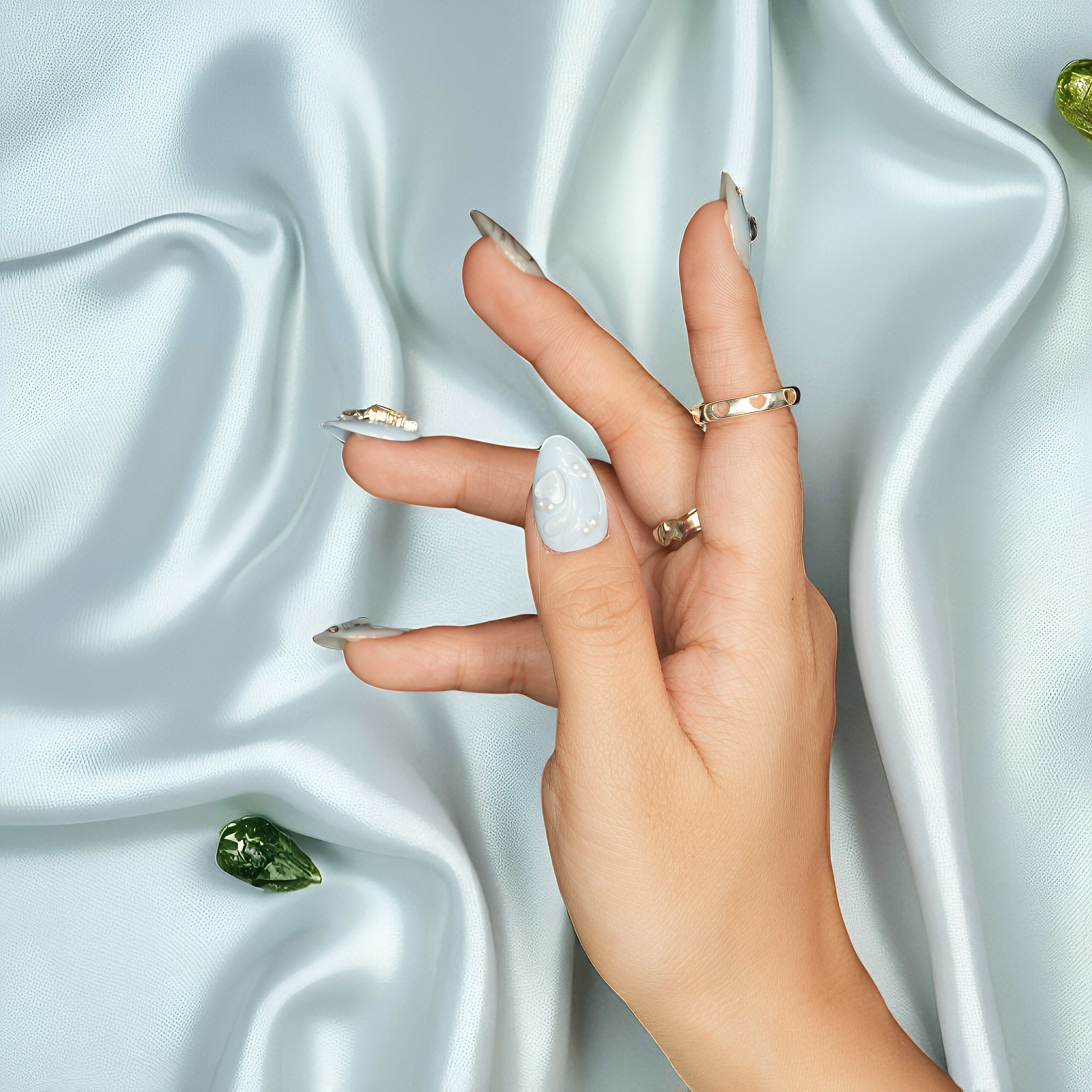 Glossy nude coffin nails featuring white heart, gems, and chrome shimmer