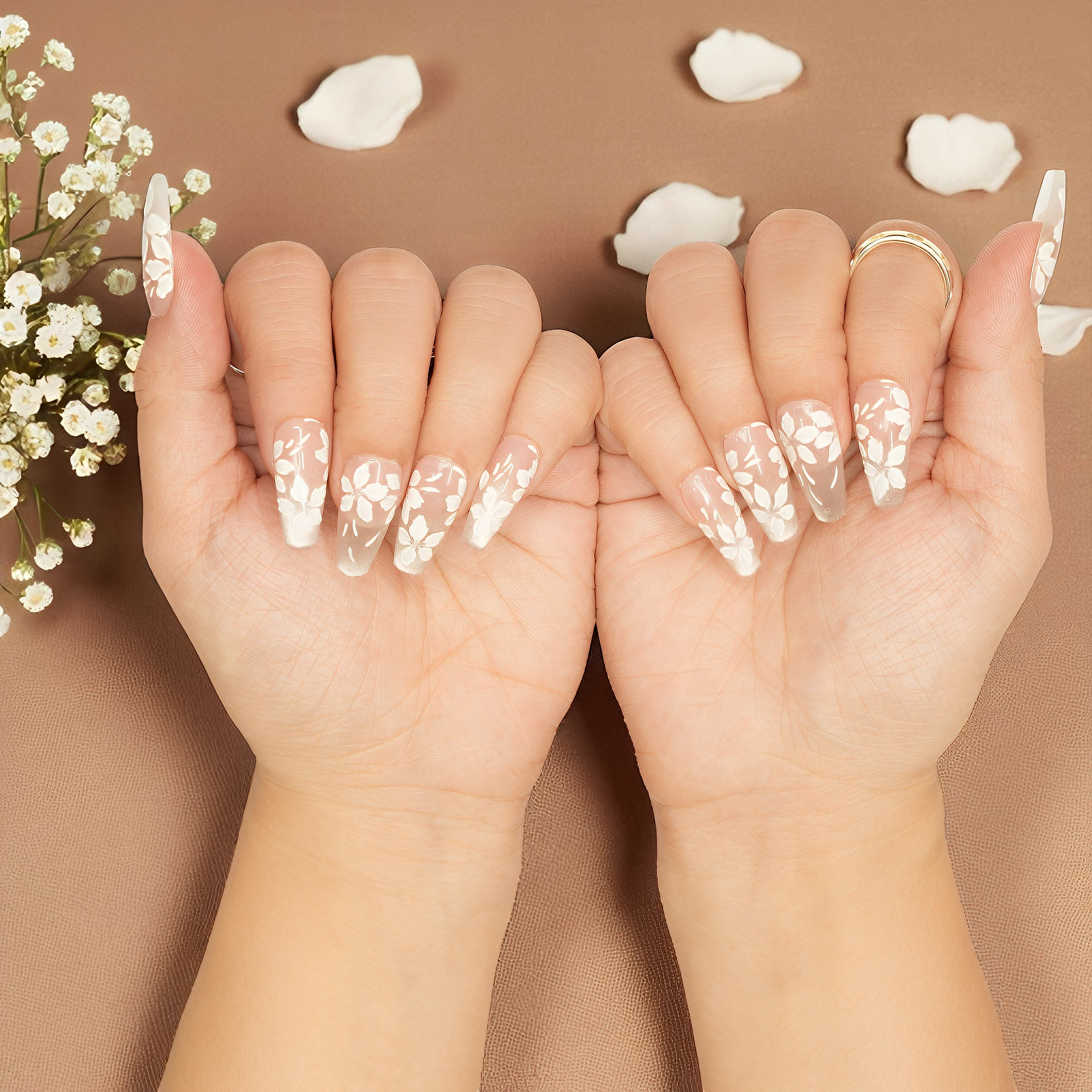 Coffin nails with soft pink hue and intricate white floral details, glue on nail set