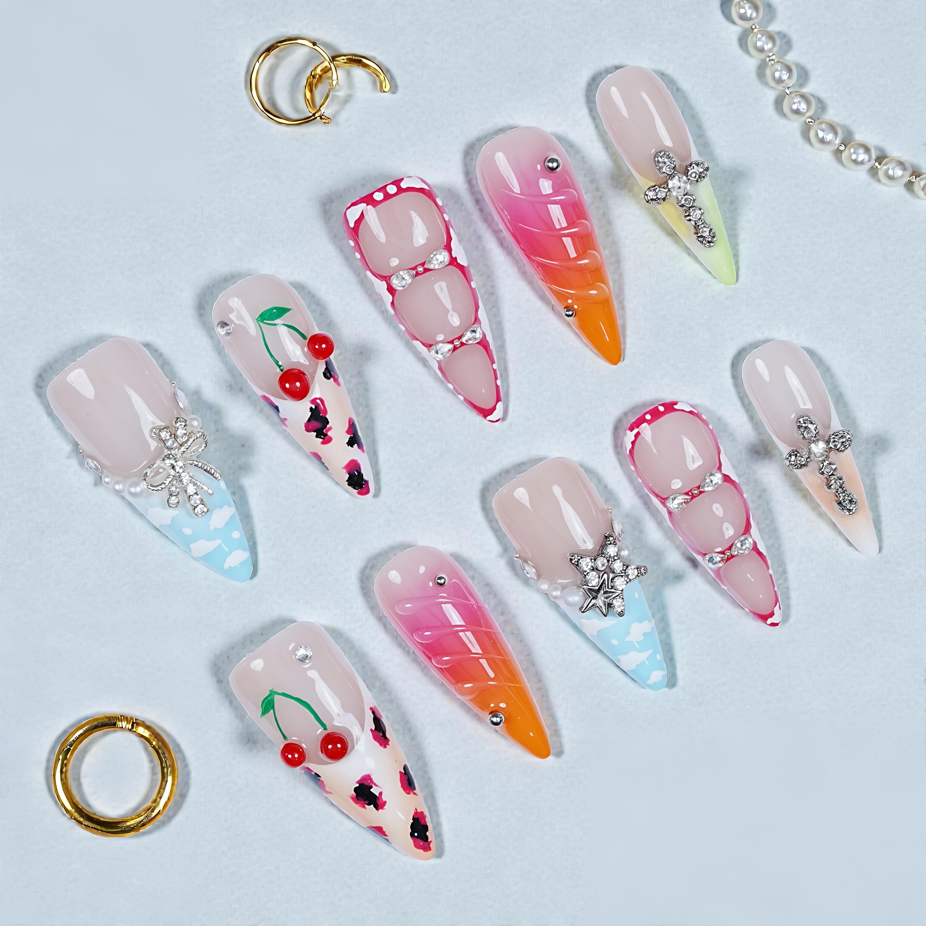 Set of decorative false nails with various designs on a light blue background