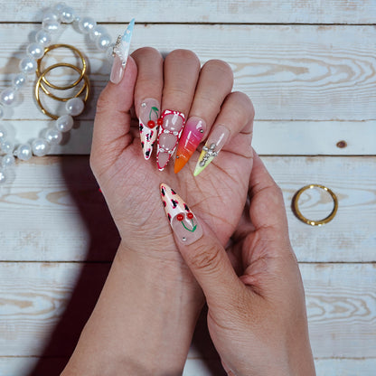 Hand with colorful nail art on a wooden surface with jewelry.