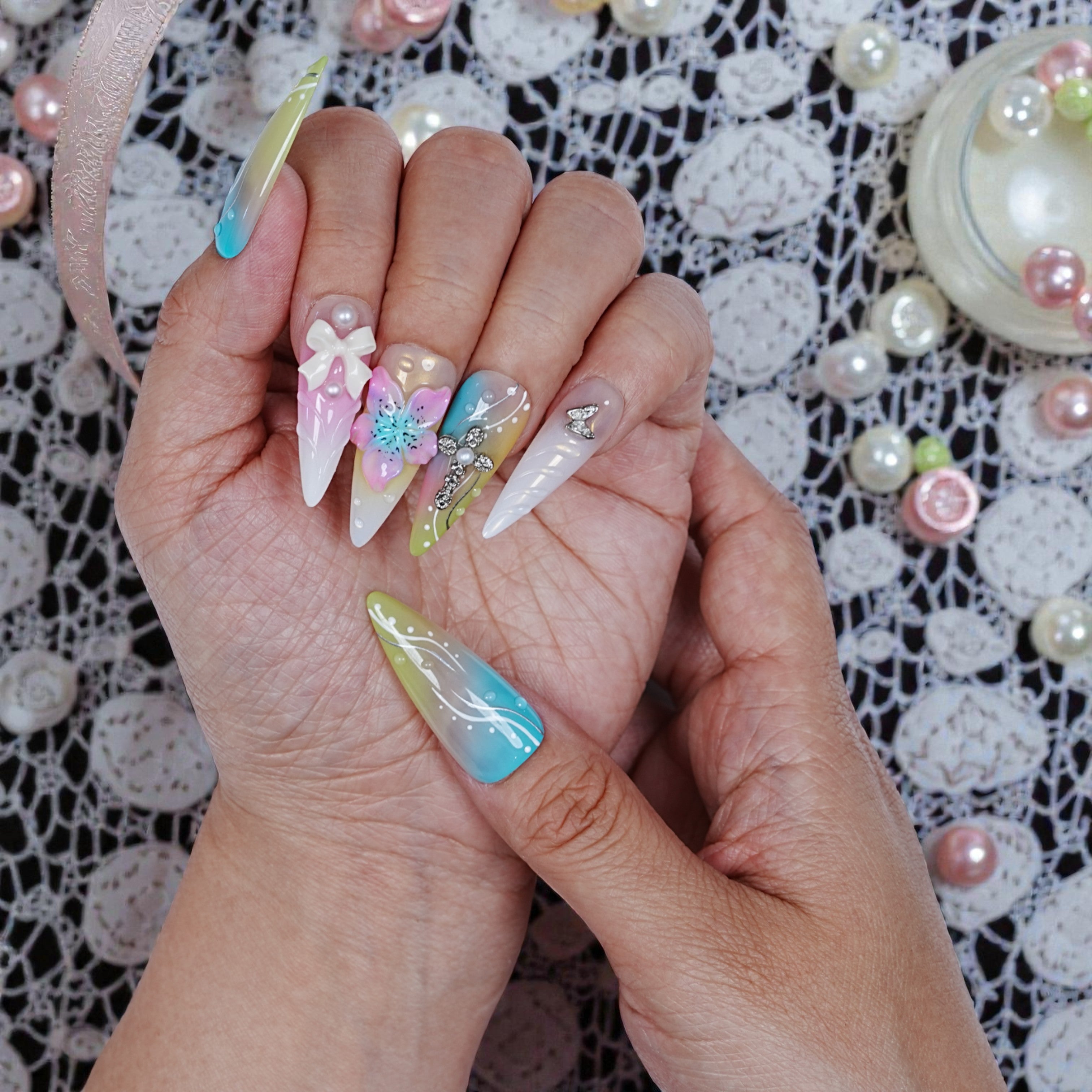 Right hand displaying pearly accents and translucent base with floral and cross designs in Aurora Belle Garden