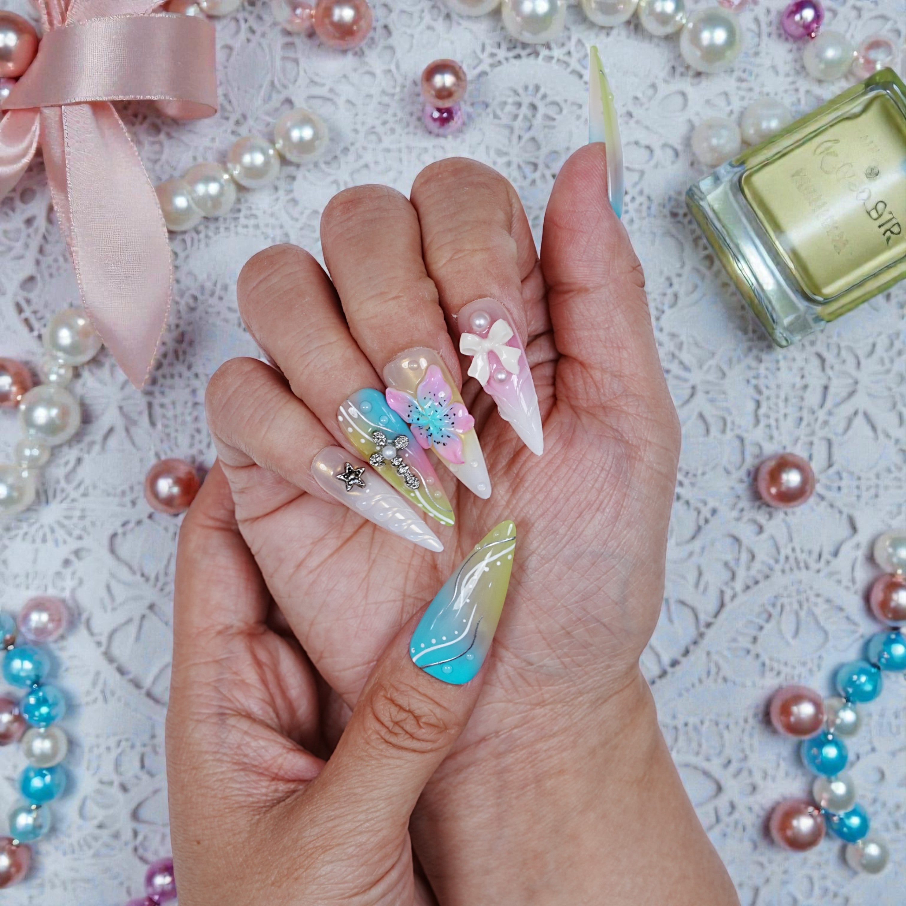 Flat lay of Aurora Belle Garden nail tips in a row, highlighting pastel jelly tones and floral layering