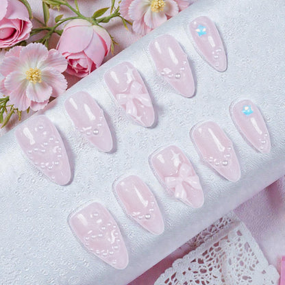 Flat lay of artificial nail set showing 3D bows, floral art, and soft shimmer finish