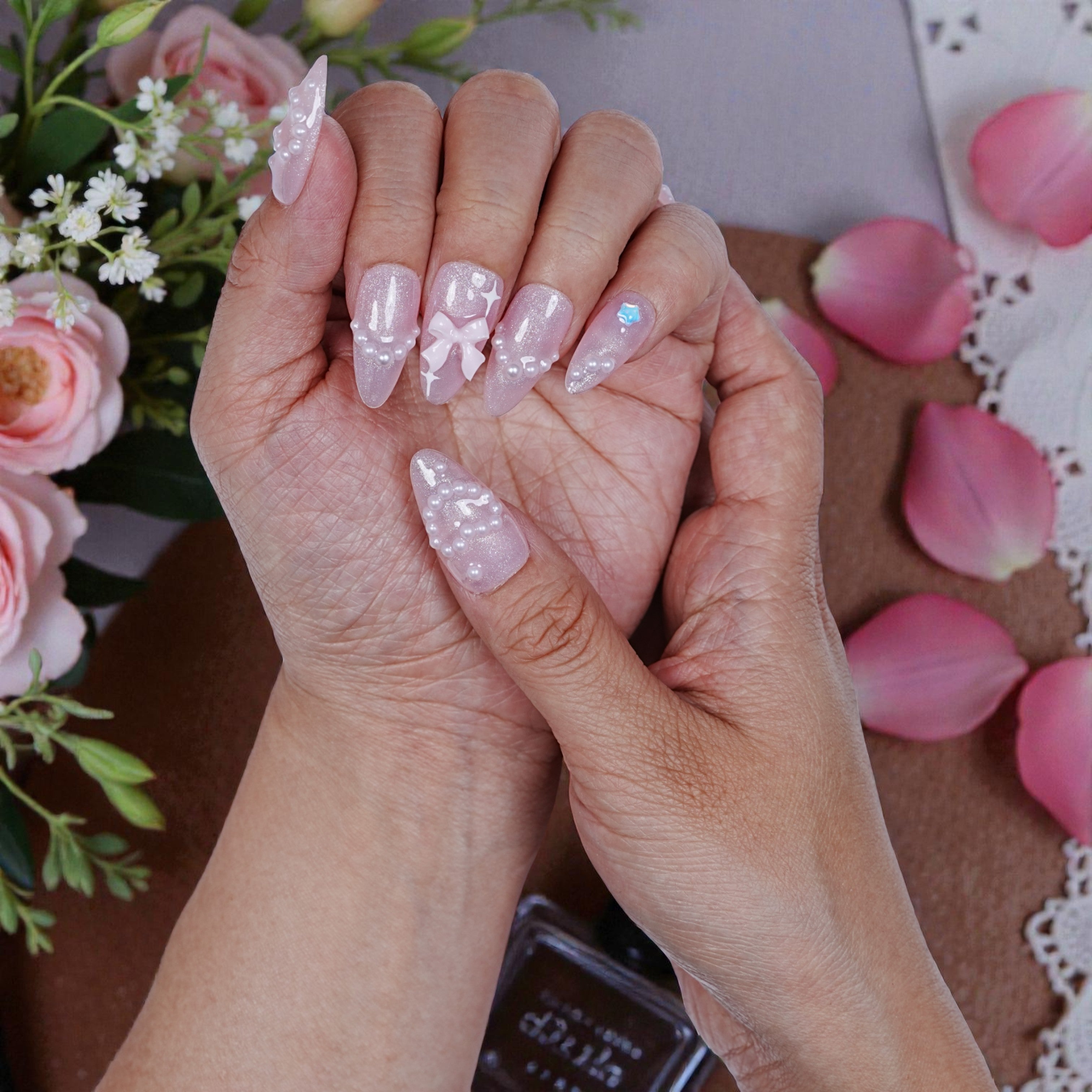 Close detail of 3D artificial nails with floral accents and blush tone