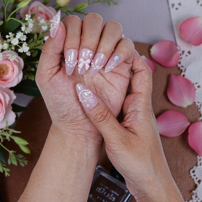 Close detail of 3D artificial nails with floral accents and blush tone