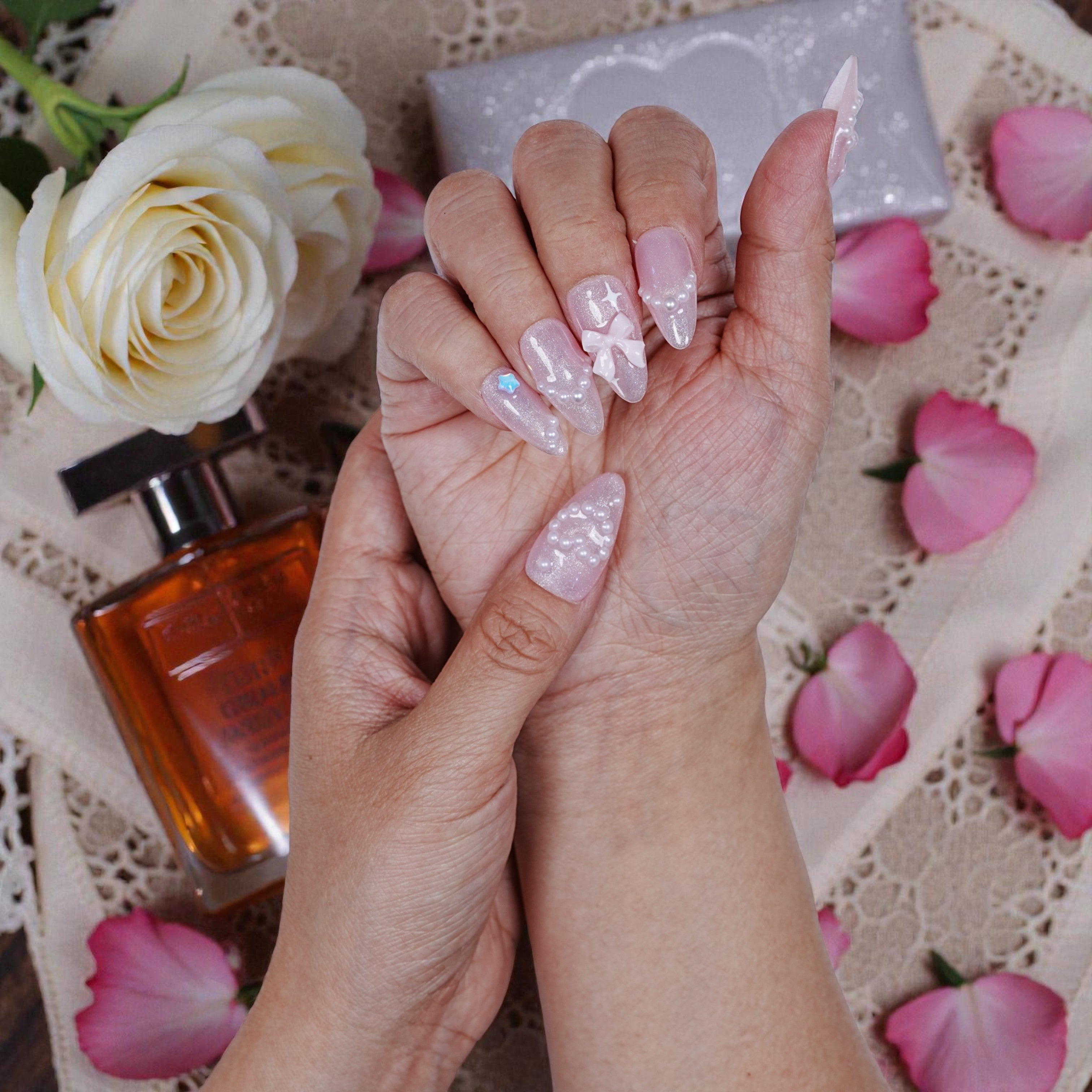 Both hands together wearing the artificial nail set, surrounded by floral props