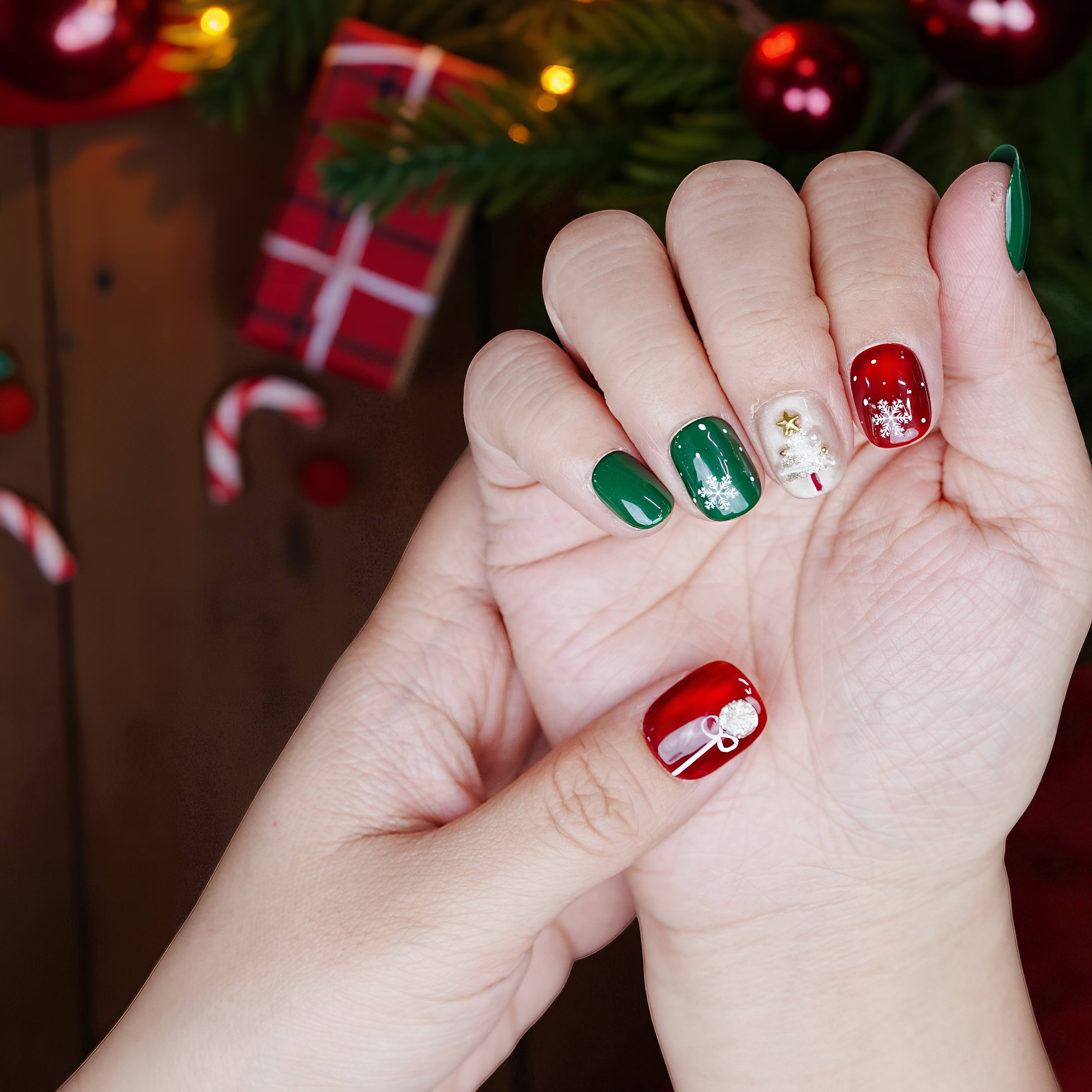 Festive nails with white sparkle, green shimmer, and red details