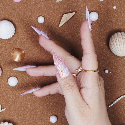 One-handed view of 3D stiletto press on nails in pearlescent pink and white with floral art and shimmer