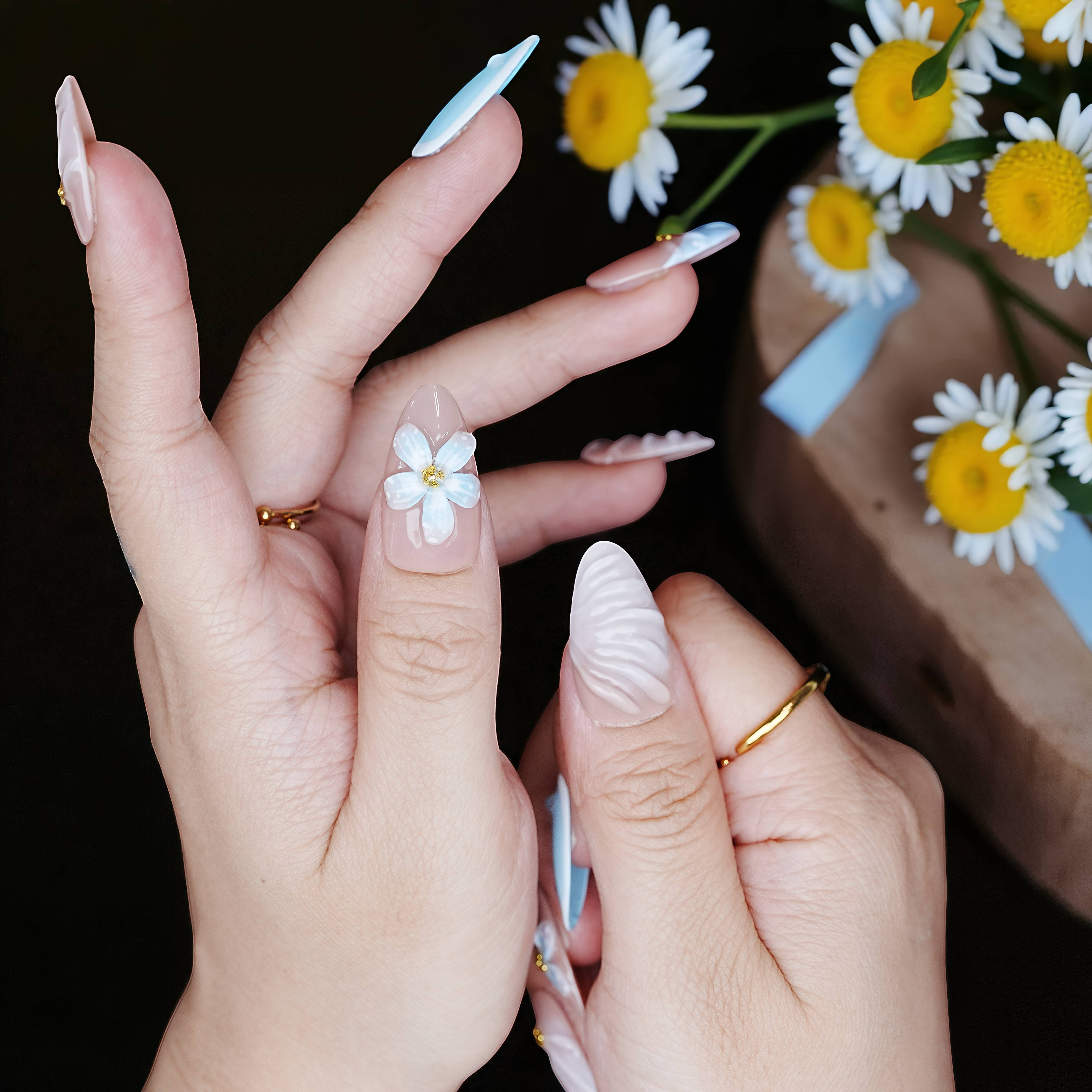 Nails styled over a dark floral background, showing shell-texture tips and raised flower accents.