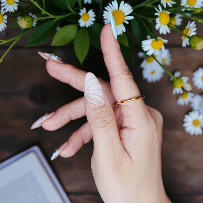 Close-up of sculpted shell designs and pastel blue tips on natural pink base, arranged with daisies.