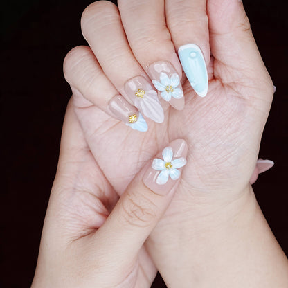 Soft-touch hand pose showing full set with sculpted shell finish, baby blue tip, and soft flower center.