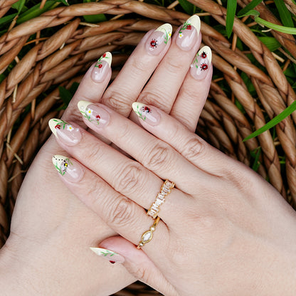 Full hand display of Garden Picnic nails with yellow French tips, floral designs, and crawling ladybug accents.