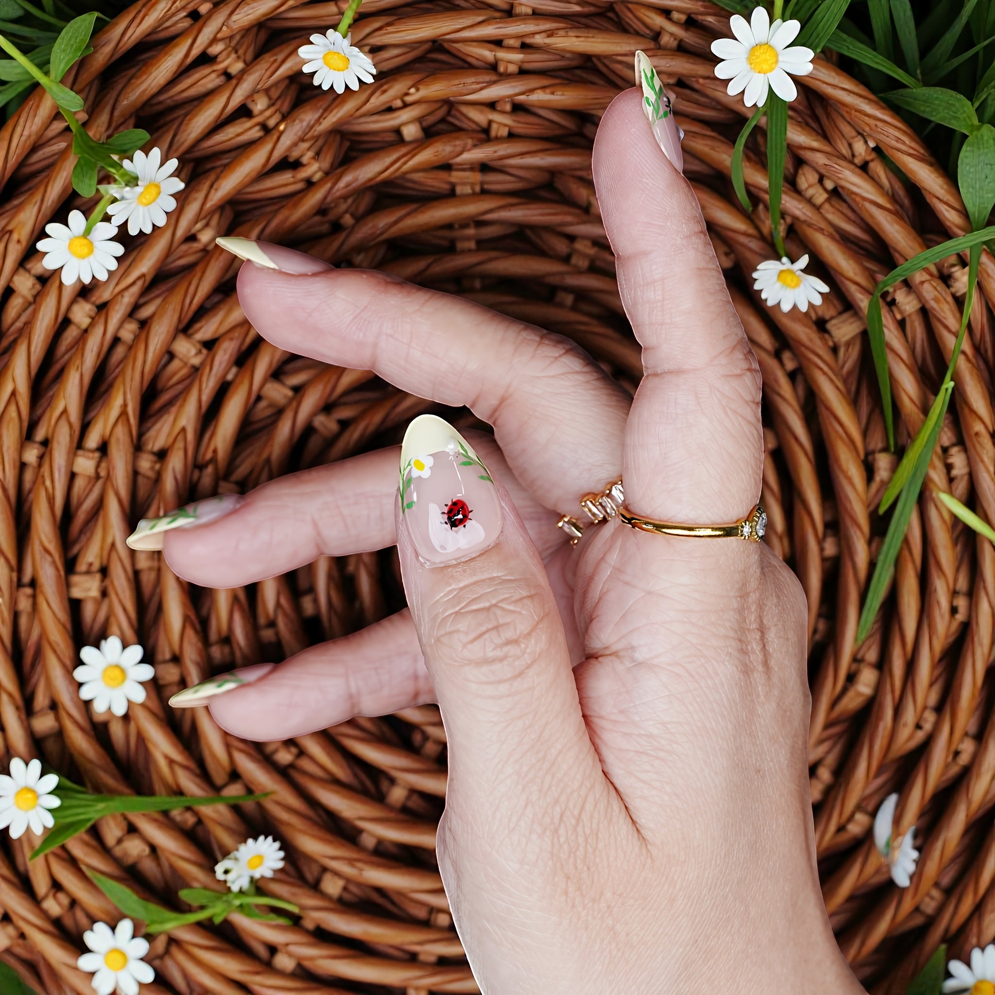 Top-down angle of thumb art featuring hand-painted daisy and ladybug on a pastel yellow tip.