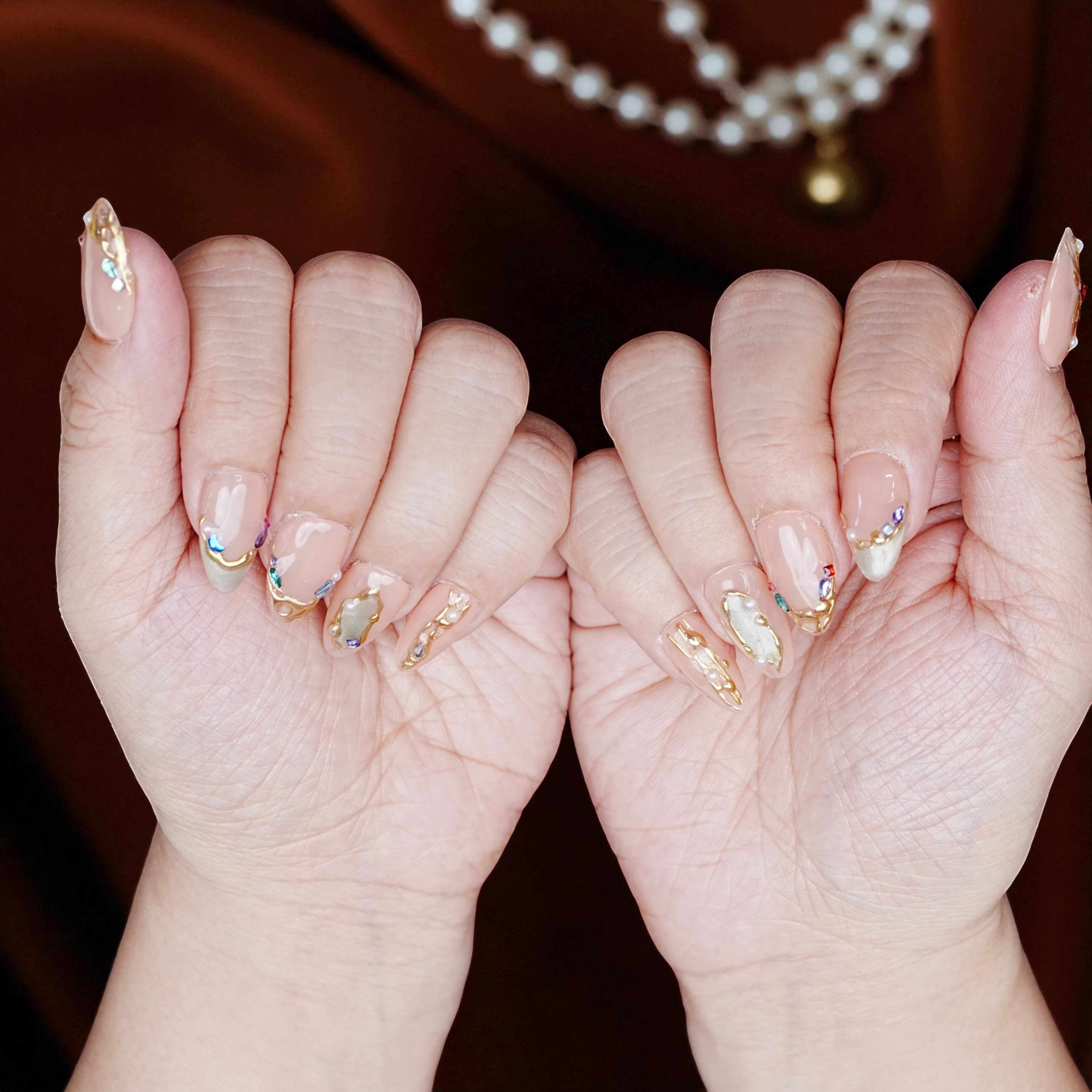Almond-shaped blush chrome nails laid out on pastel background